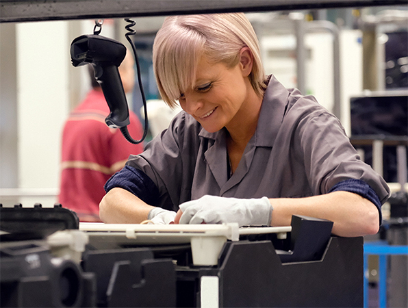 Due dipendenti ispezionano il case esterno del MacBook sulle griglie di anodizzazione al titanio presso uno stabilimento Apple.