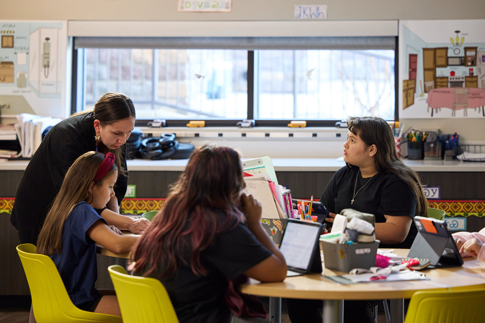 Imagen de Minnia Whitener mientras trabaja con tres estudiantes en un aula de la Cherokee Immersion School en Tahlequah, Oklahoma.