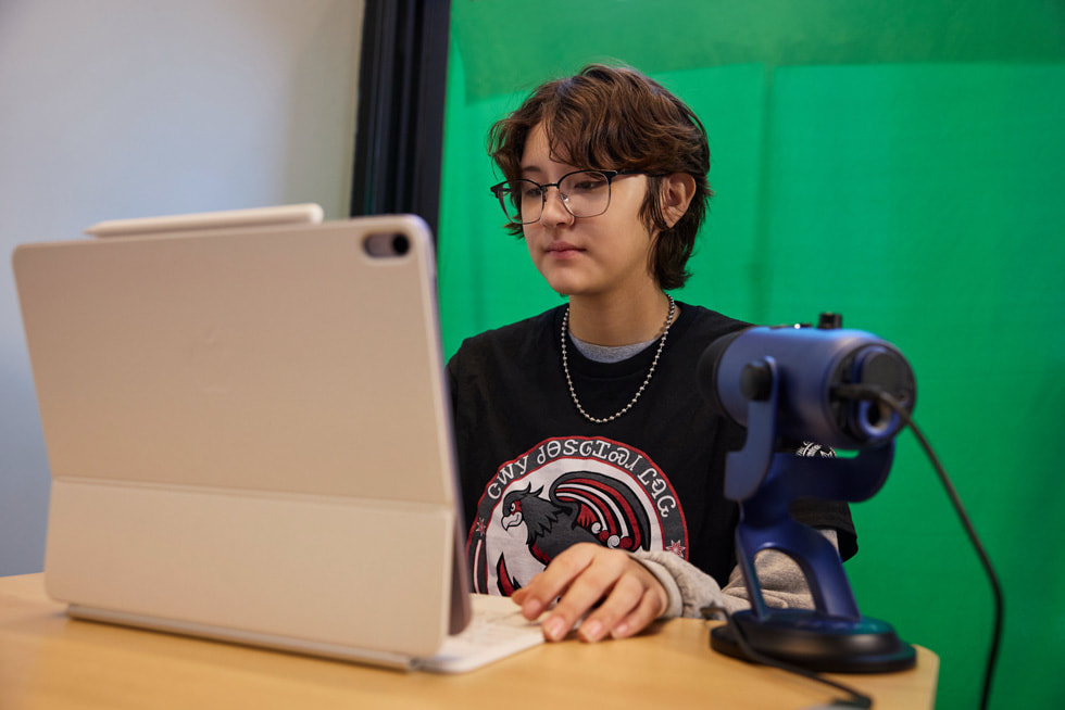 Imagen de un estudiante trabajando en el iPad con un micrófono que también está apoyando en el escritorio.