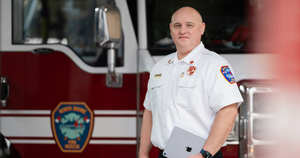 Le chef du service d’incendie devant un camion de pompiers, un iPad à la main et une Apple Watch au poignet