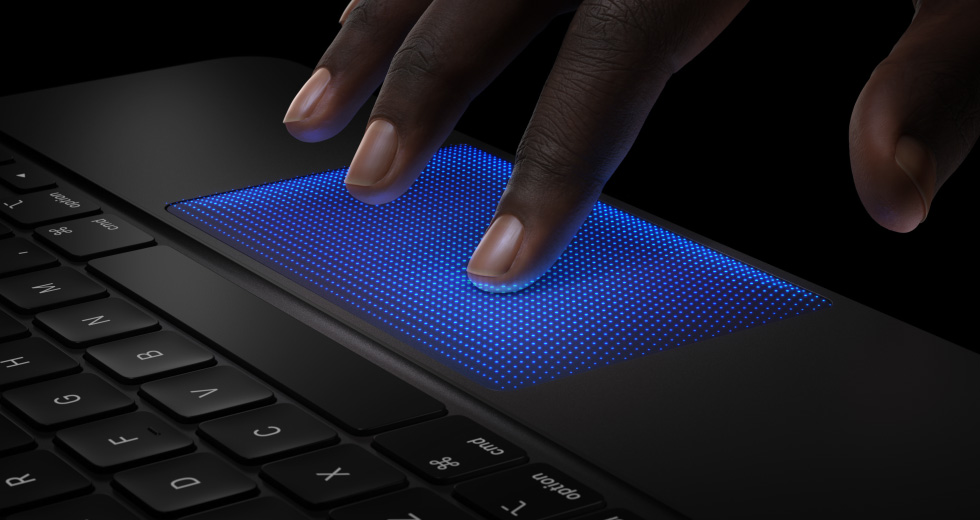 Animatie van een hand met vingers die boven de trackpad van Magic Keyboard zweven, wijsvinger met blauwe schaduw die een tikbeweging laat zien om voelbare feedback te demonstreren